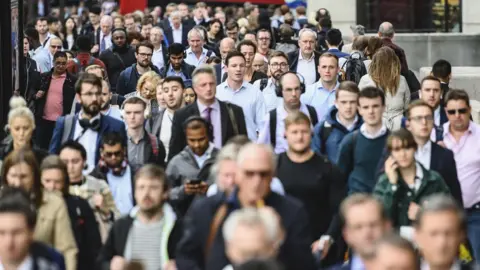 Getty Images Crowds of commuters walking down a busy street