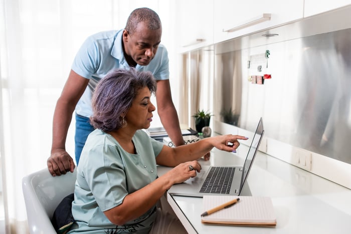 Two people look at a computer and discuss something. 